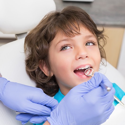 Pediatric dentist examining young patient's smile