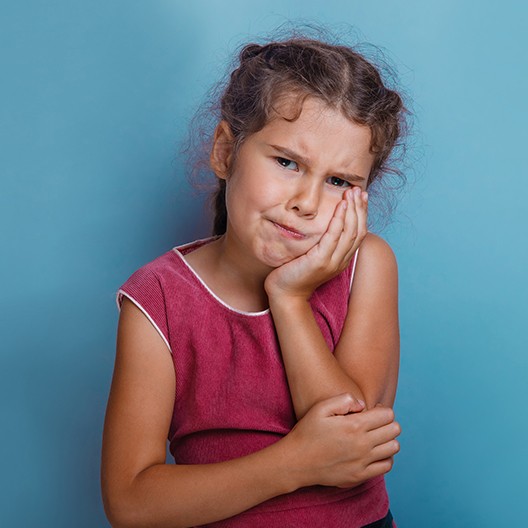 Child with toothache holding cheek