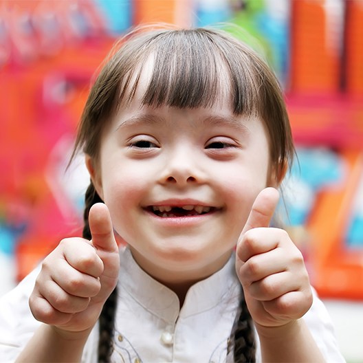 Little girl smiling giving two thumbs up after special needs dentistry visit