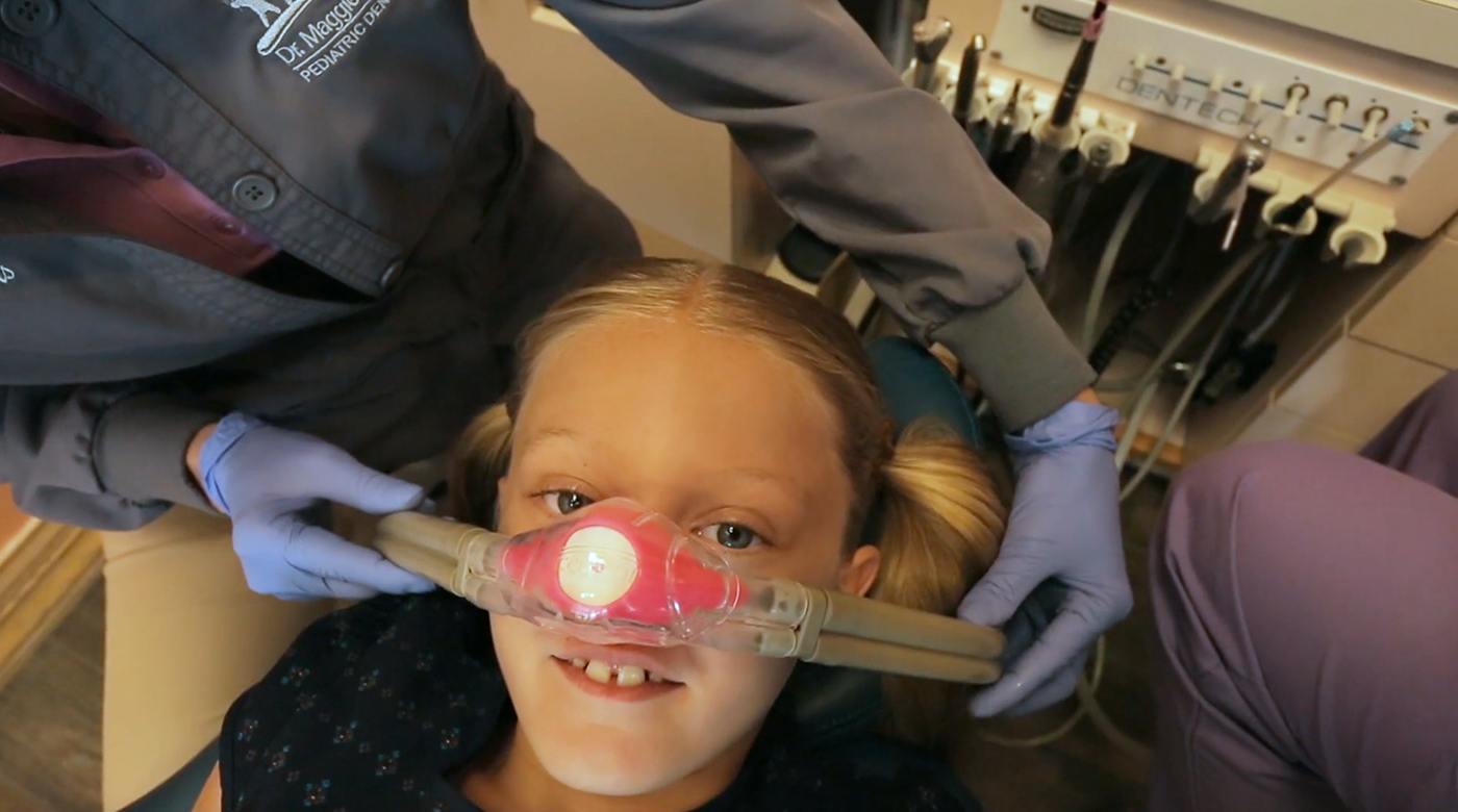 Dental team member placing nitrous oxide nasal mask on child