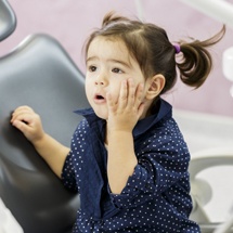 Little girl in need of emergency dentistry holding cheek