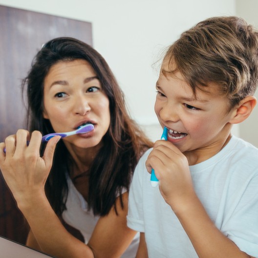 Mother and child brushing teeth together