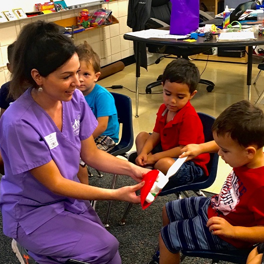 Dental team member teaching kids to brush teeth