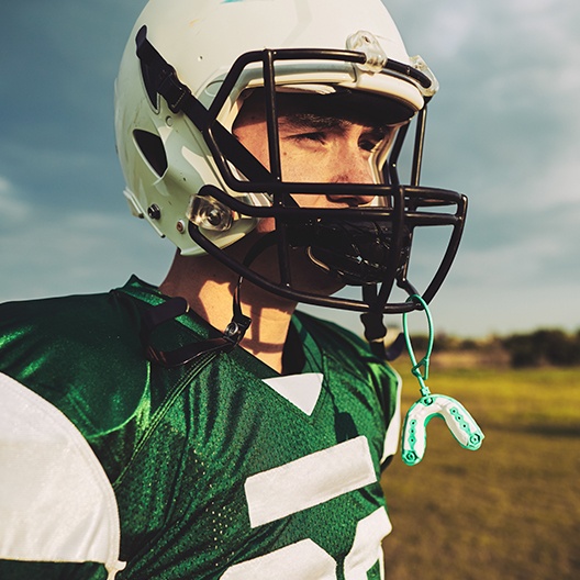 A football player wearing a helmet with his mouthguard hanging off it