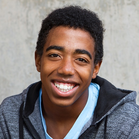 Teen boy smiling after dental crown treatment