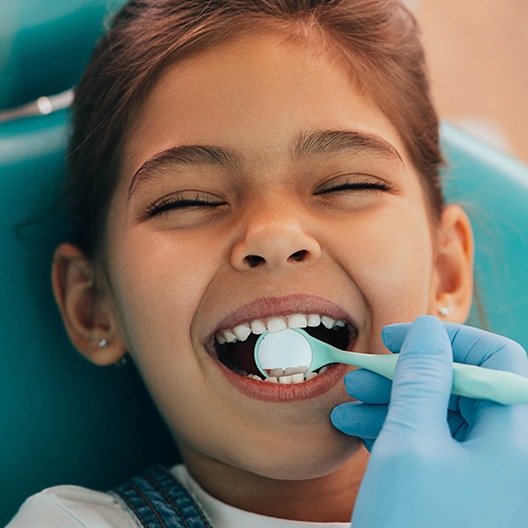 Dentist checking child's tooth colored filling