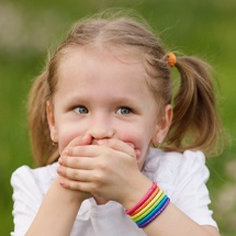 Little girl in need of emergency dentistry covering smile