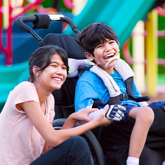 Teen girl smiling with laughing boy in wheelchair