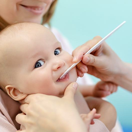 A mother holding her baby at the dentist’s office while the pediatric dentist cleans their teeth