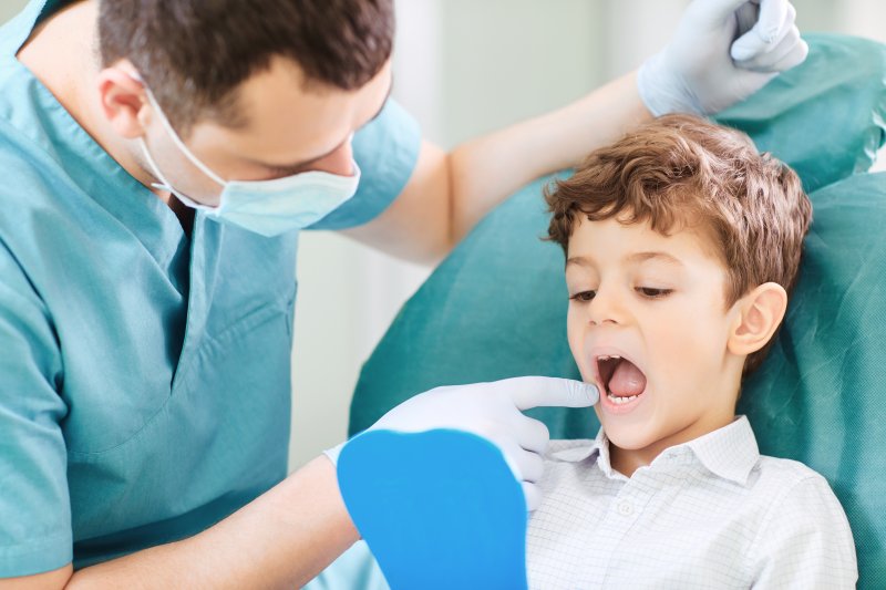 Dentist and child checking teeth in mirror