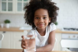 child holding water after showing signs of dehydration