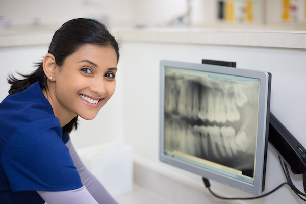 woman in scrubs examining dental x-ray