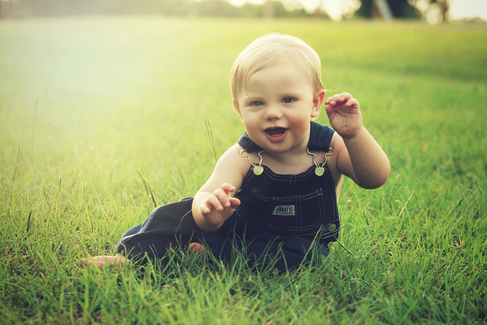baby sitting in field and smiling