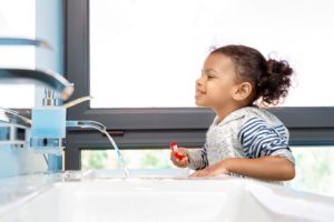 Little girl brushing her teeth in front of mirror