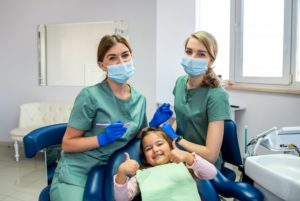 a woman pediatric dentist cleaning a child's teeth